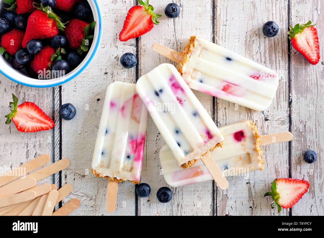 Gruppe von hausgemachten Mixed berry Joghurt Eis am Stiel. Ansicht von oben auf einem urigen weiß Holz Hintergrund. Stockfoto