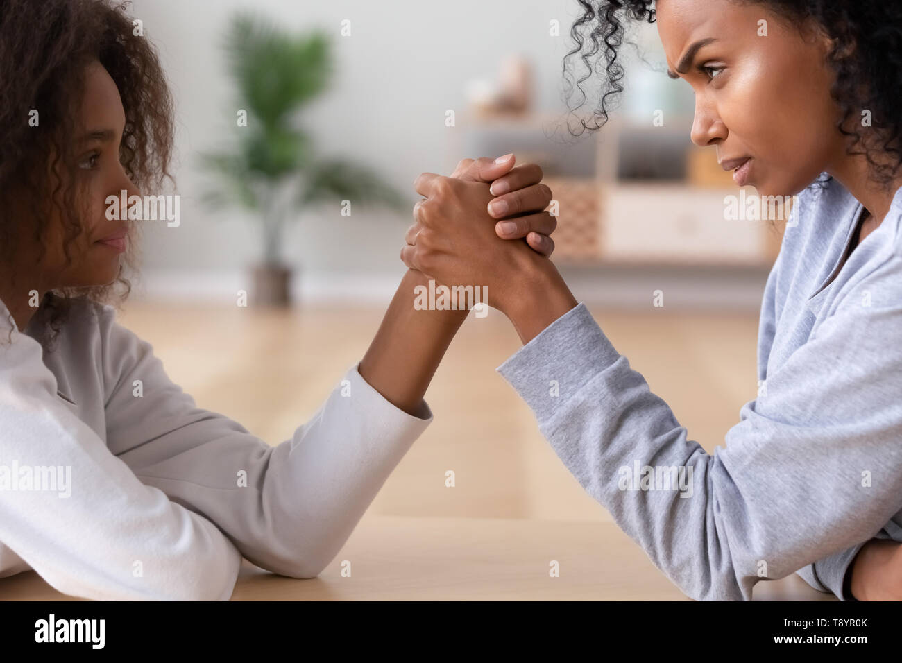 African American Teen Tochter und Mutter Arm Wrestling Familie Konflikt Stockfoto