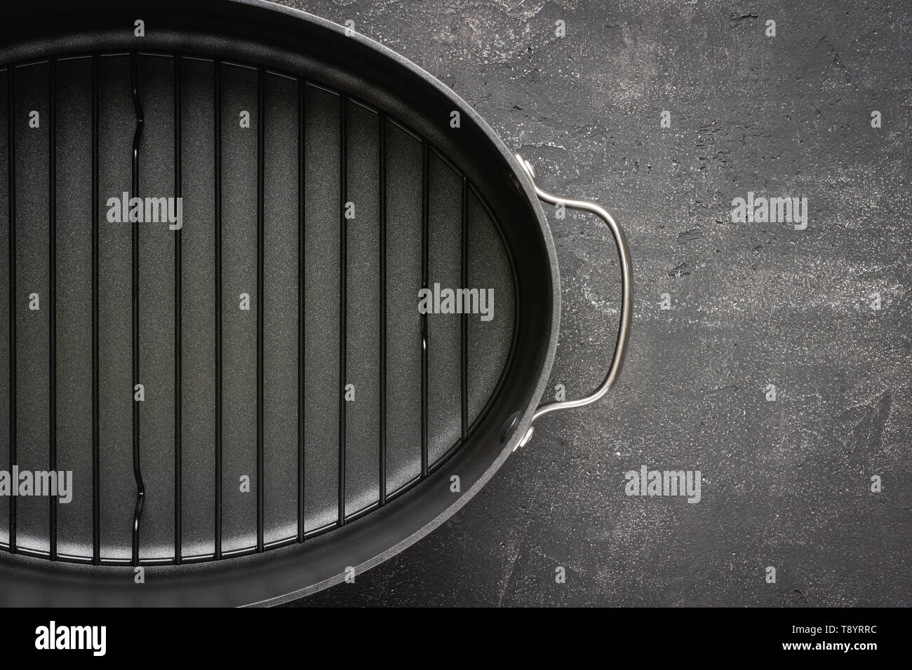 Leere graue Nonstick Auflaufform mit Griffen auf dunklem Stein Oberfläche. Kulinarische Hintergrund. Stockfoto