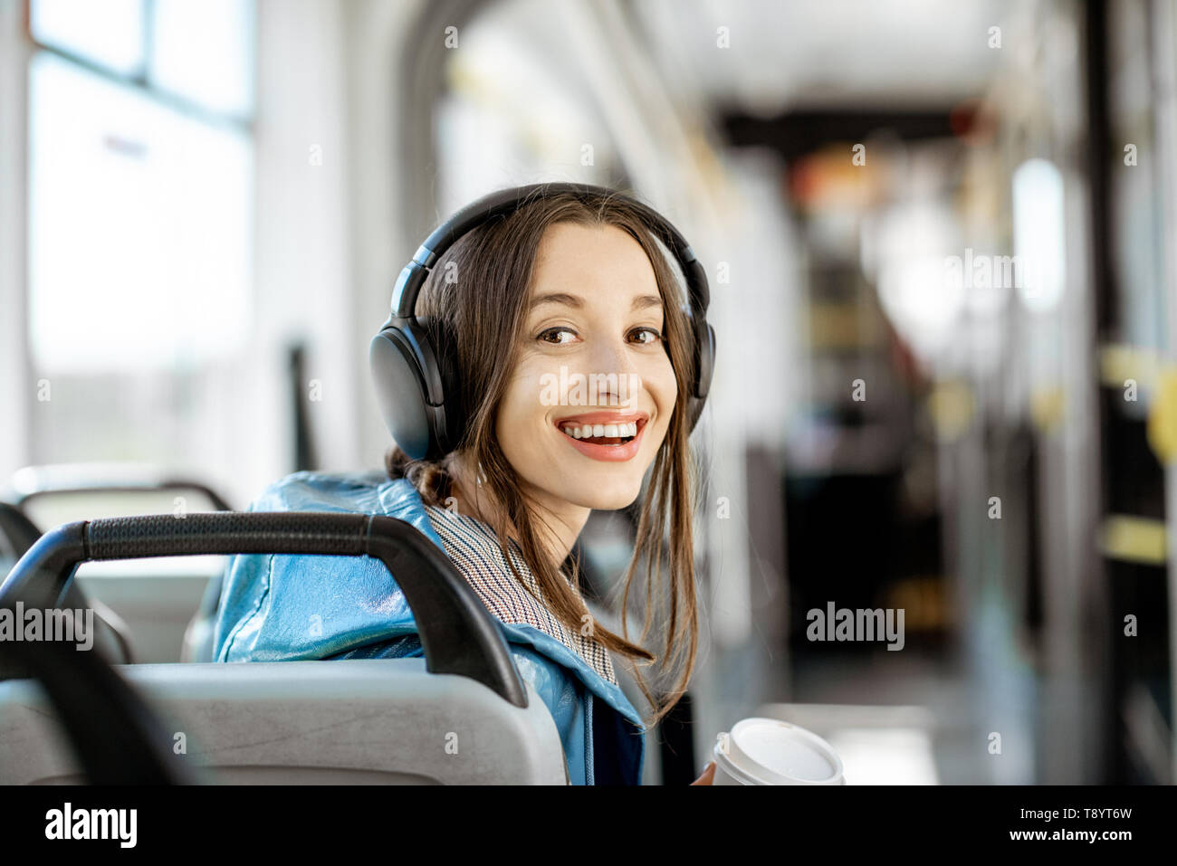 Porträt einer jungen Frau Passagier genießen Urlaub im öffentlichen Verkehr, sitzend mit Kopfhörern in der modernen Straßenbahn Stockfoto