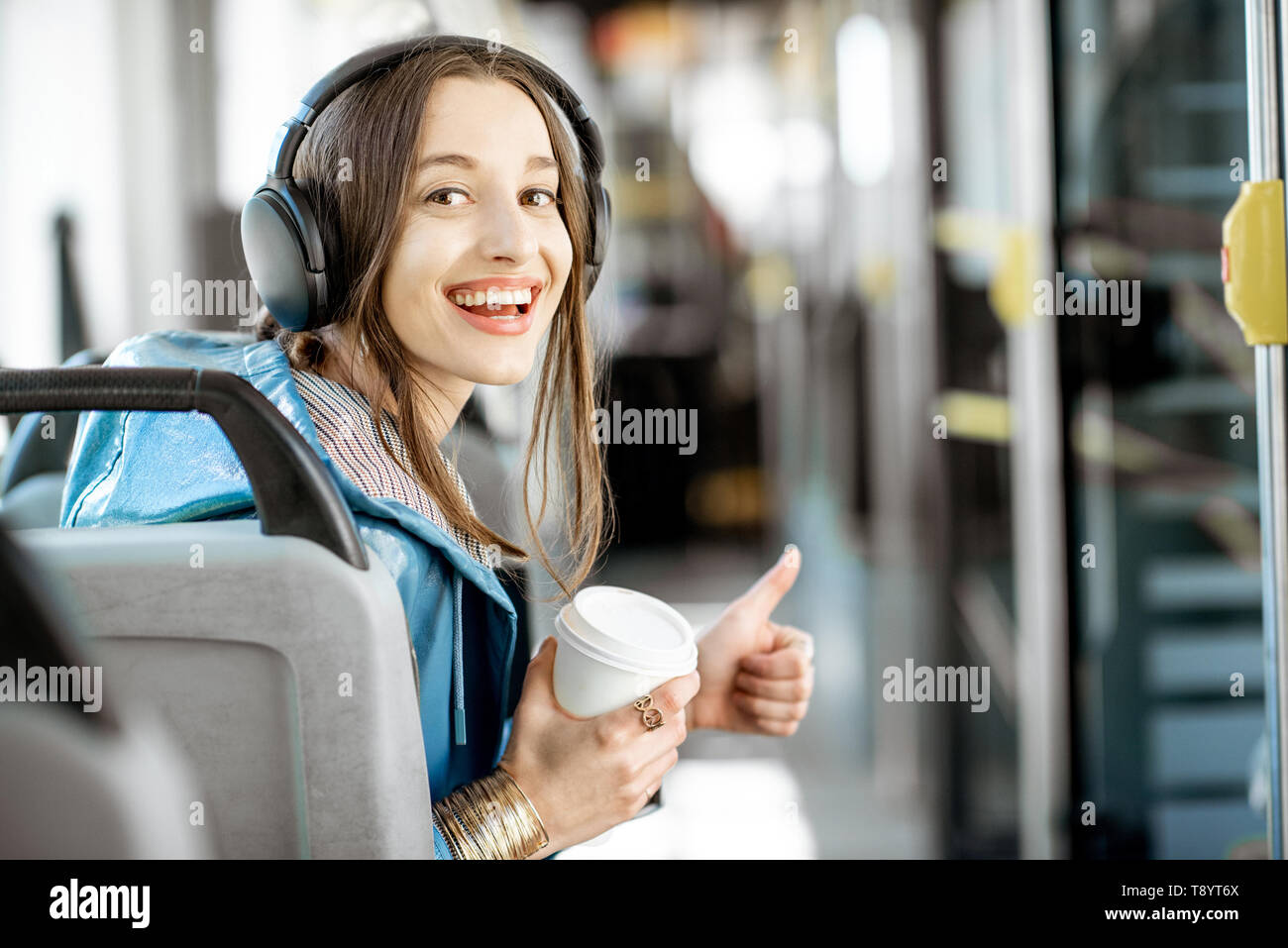 Porträt einer jungen Frau Passagier genießen Urlaub im öffentlichen Verkehr, sitzend mit Kopfhörern in der modernen Straßenbahn Stockfoto