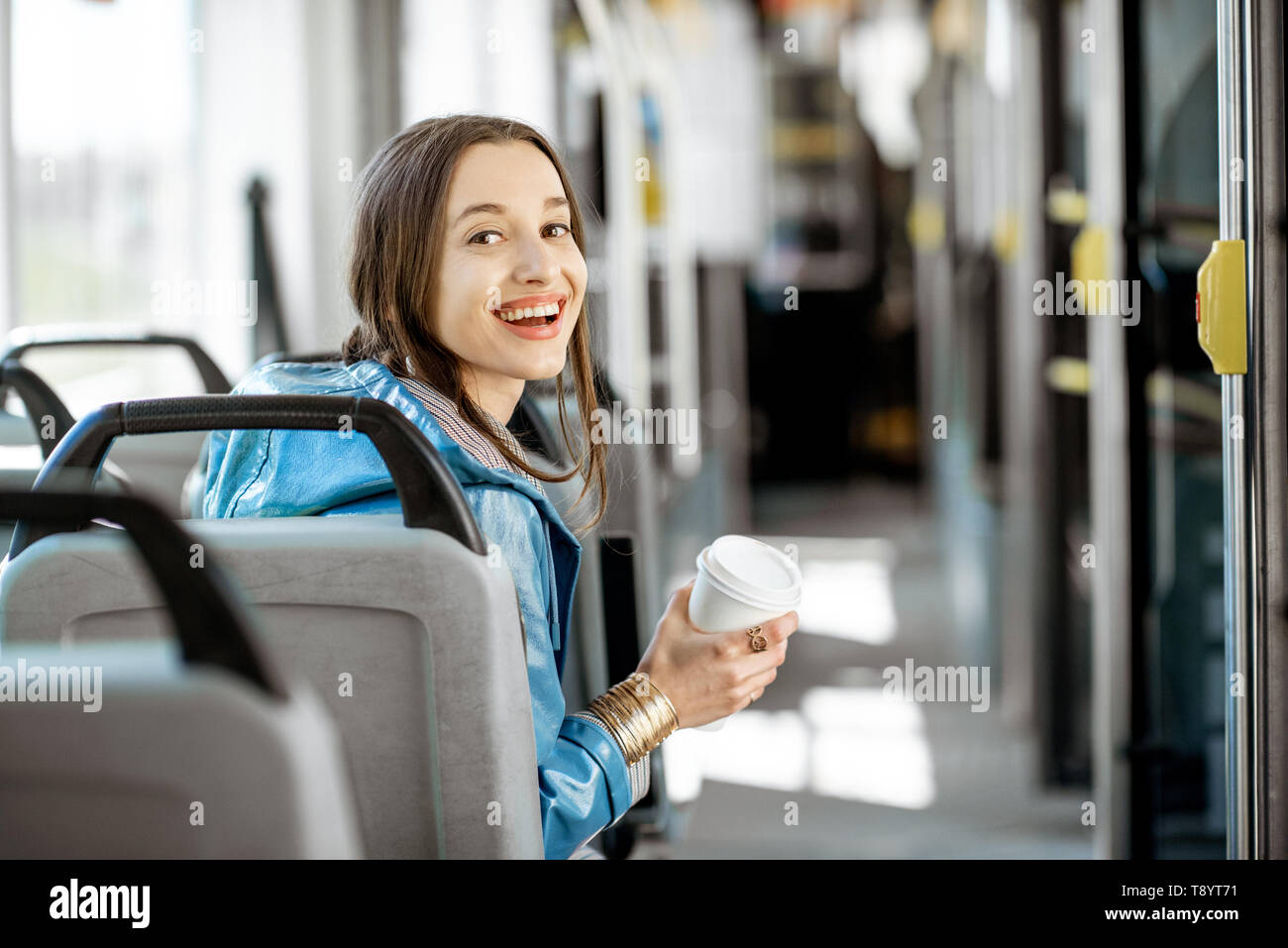 Porträt einer jungen Frau Passagier genießen Urlaub im öffentlichen Verkehr, sitzend mit Kaffee in der modernen Straßenbahn, Rückansicht Stockfoto