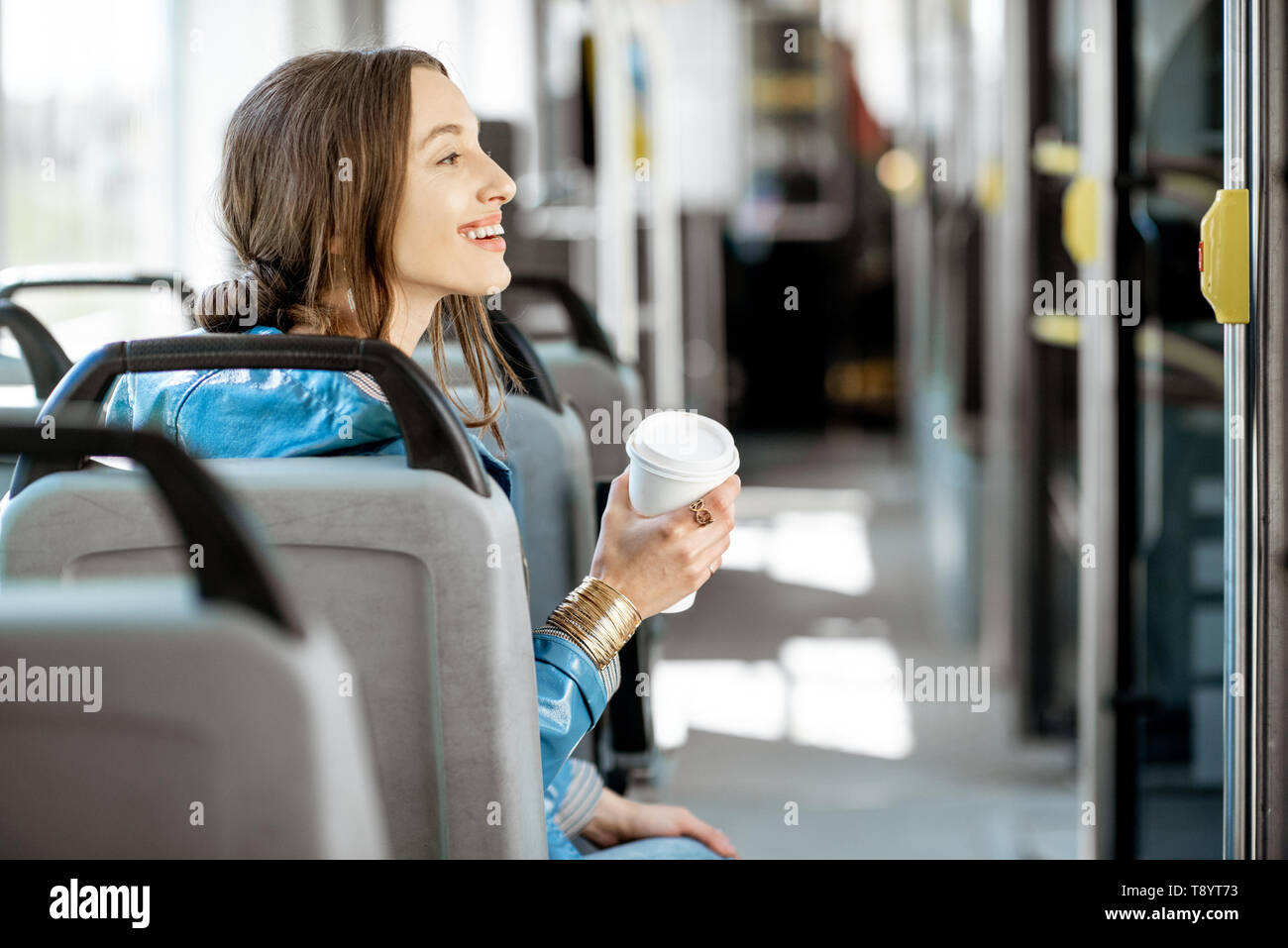 Porträt einer jungen Frau Passagier genießen Urlaub im öffentlichen Verkehr, sitzend mit Kaffee in der modernen Straßenbahn, Rückansicht Stockfoto