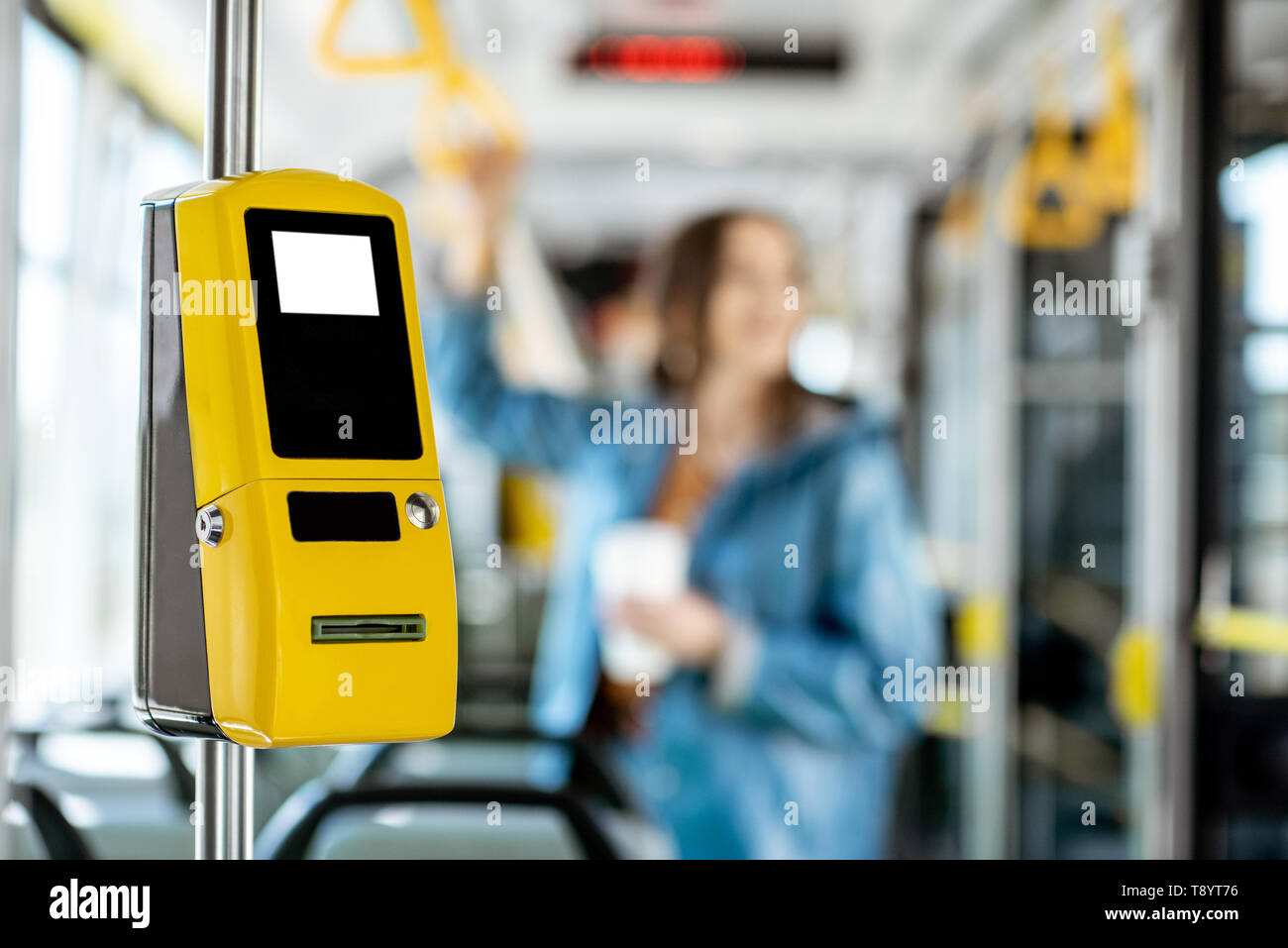 Gelbe Fahrkartenautomaten in der modernen Tram mit weiblichen Passagier auf dem Hintergrund Stockfoto
