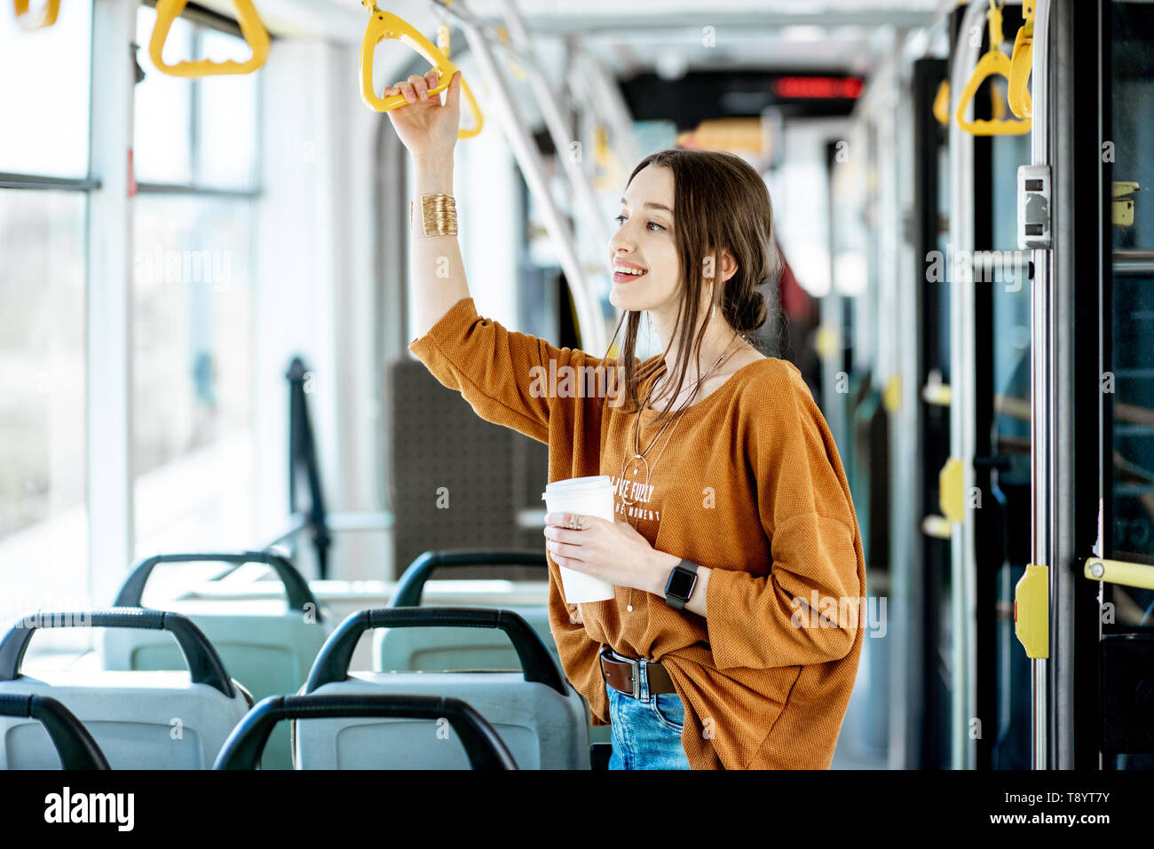 Junge und Glückliche Passagiere genießen Reise an die öffentlichen Verkehrsmittel, mit Kaffee in der modernen Straßenbahn stehend Stockfoto