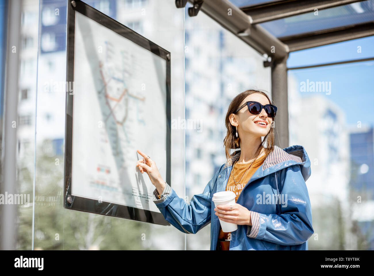 Frau auf der Suche nach der Regelung des öffentlichen Verkehrs während an der Straßenbahnhaltestelle im Freien stehend Stockfoto