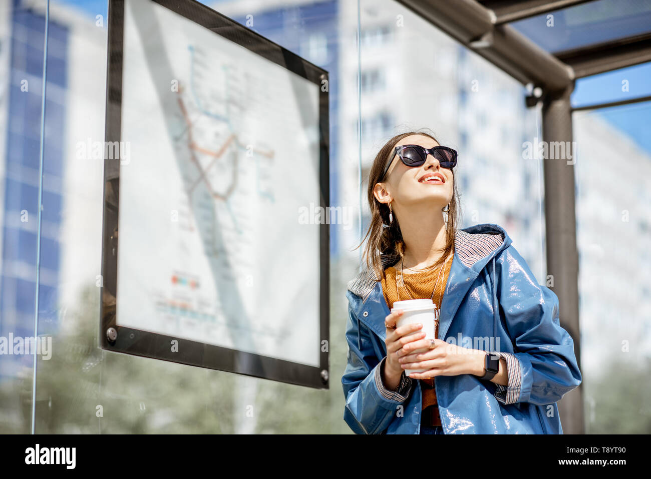Junge stilvolle Frau wartet auf den öffentlichen Verkehr und die Moderne tram station im Freien stehend Stockfoto