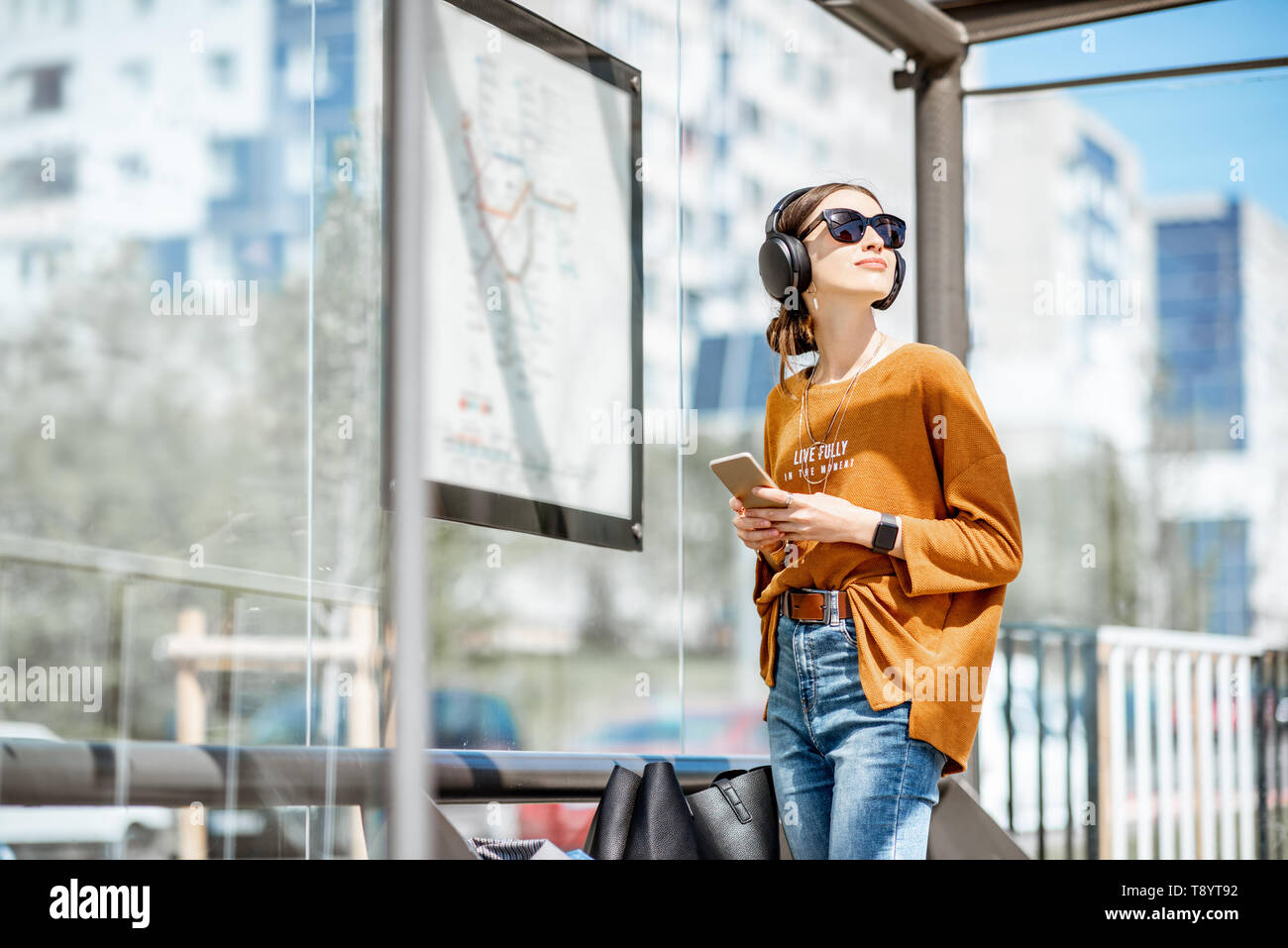 Junge stilvolle Frau wartet auf den öffentlichen Verkehr und die Moderne tram station im Freien stehend Stockfoto