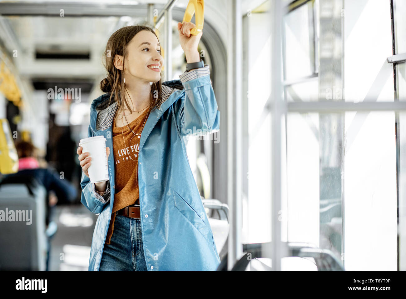 Junge Frau Passagier genießen Reise an die öffentlichen Verkehrsmittel, mit Kaffee in der modernen Straßenbahn stehend Stockfoto