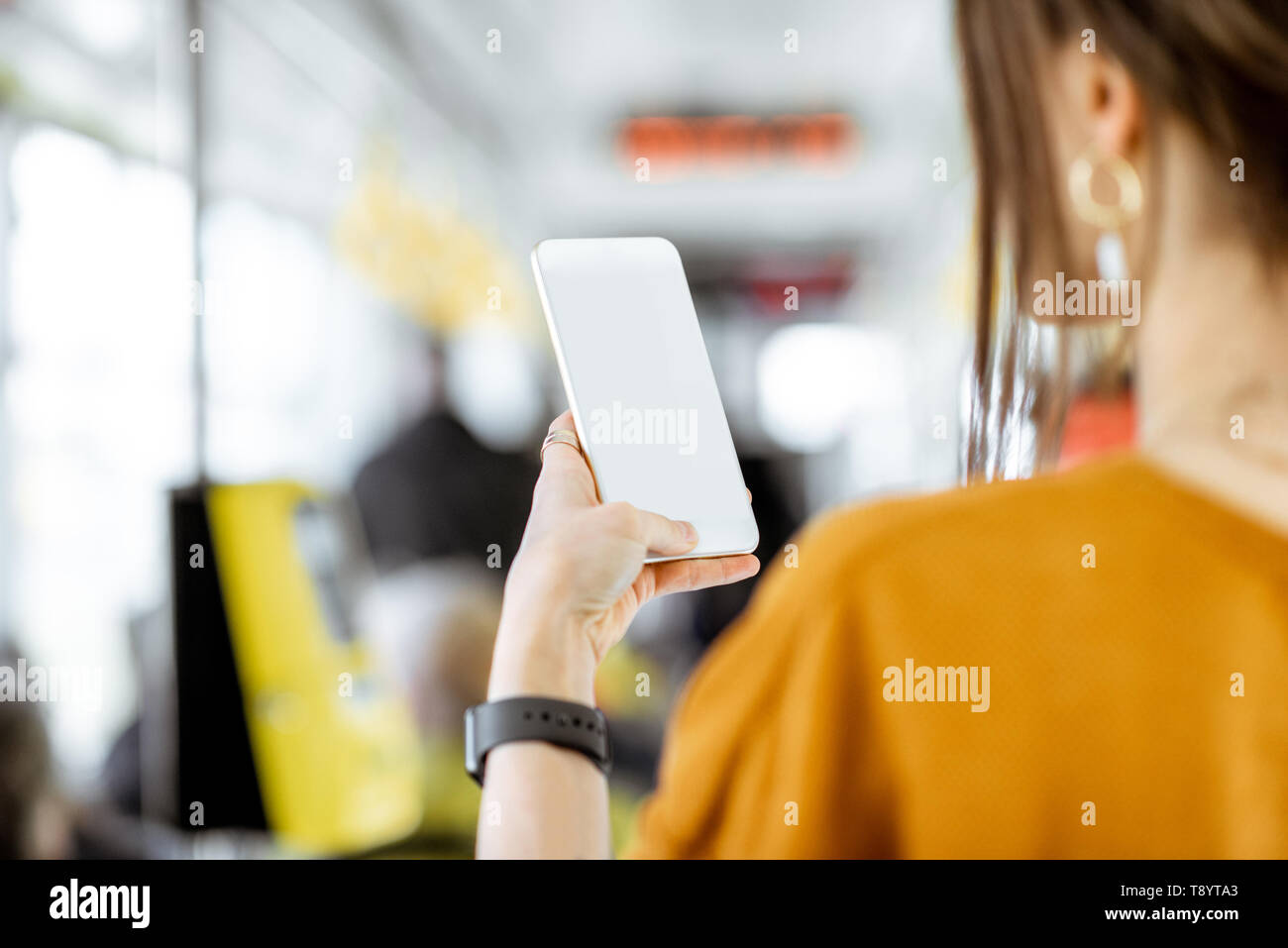 Frau mit Telefon mit leeren Bildschirm Paste zu kopieren, während in der Straßenbahn stehend Stockfoto