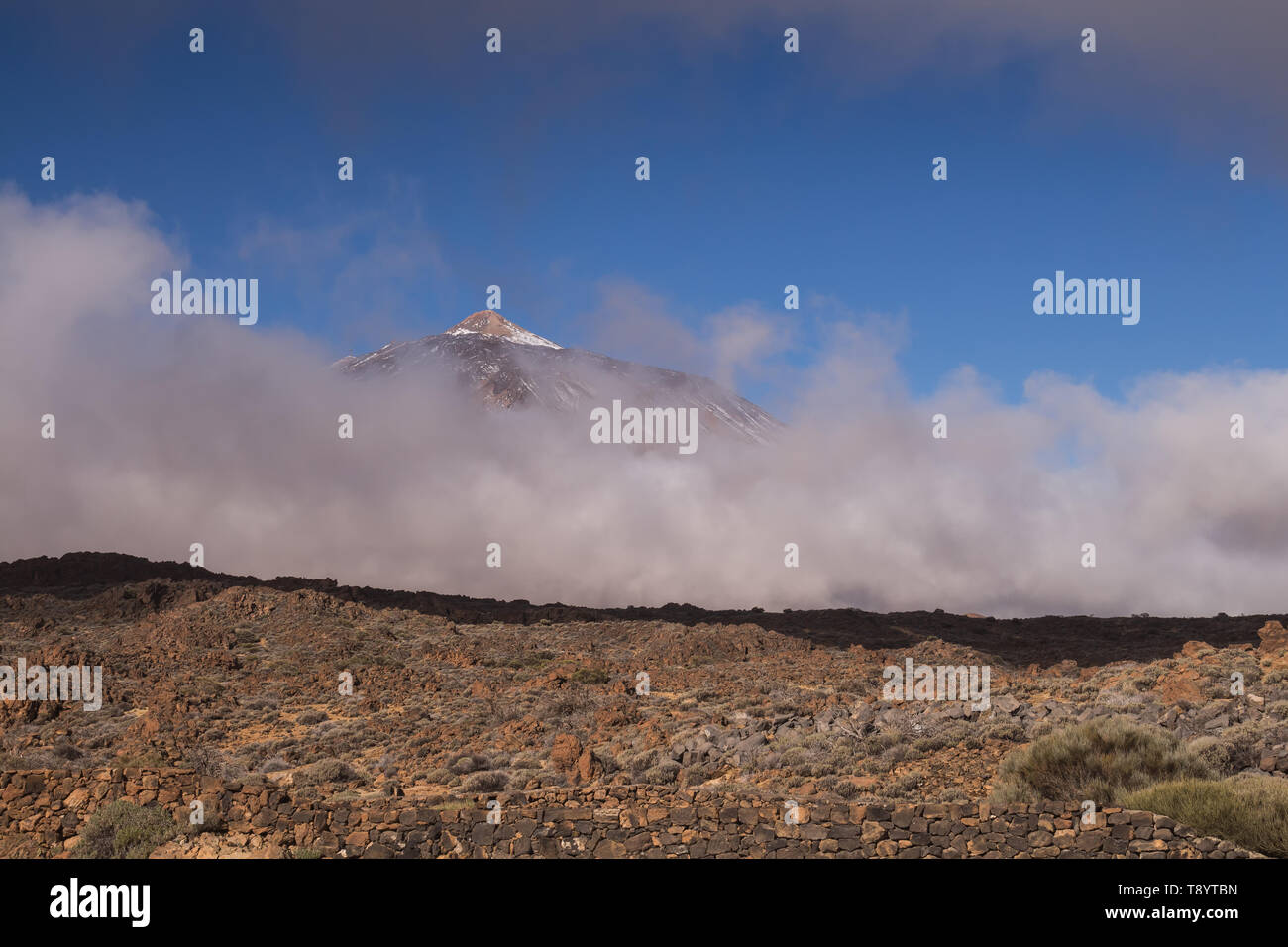 Tal von Lavasteinen. Berg Pico del Teide mit weißem Schnee Flecken, die teilweise durch die Wolken bedeckt. Strahlend blauen Himmel. Nationalpark Teide, Tene Stockfoto