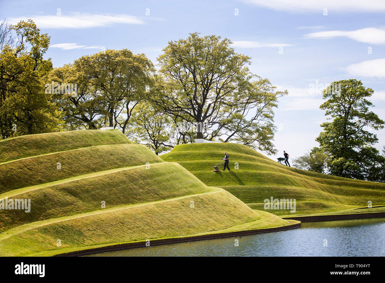 Gärtner das Gras auf die Zellen des Lebens Landschaftsformen durch Landschaftsarchitekt Charles Jeneks, einer der standortspezifischen Skulpturen auf dem Gelände des Jupiter Artland, Edinburgh erstellt mähen. Stockfoto