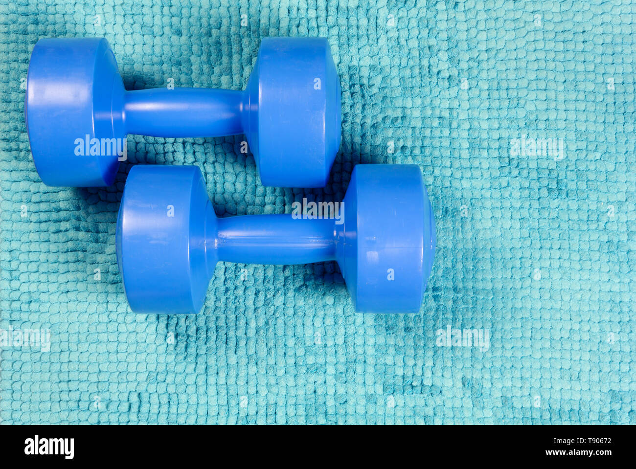 Zwei blaue Kurzhanteln auf einem türkisfarbenen Wolldecke Stockfoto