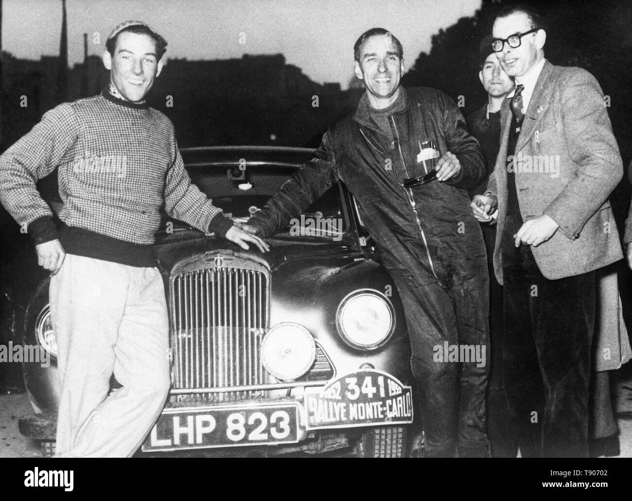 Stirling Moss (l) und sein Beifahrer John Cooper und Desmond Scannell Lächeln, als sie versammeln sich rund um die Motorhaube ihres Autos in Monte Carlo, nach Abschluss der 2.000 km langen Reisen die Rallye Monte Carlo. Stockfoto