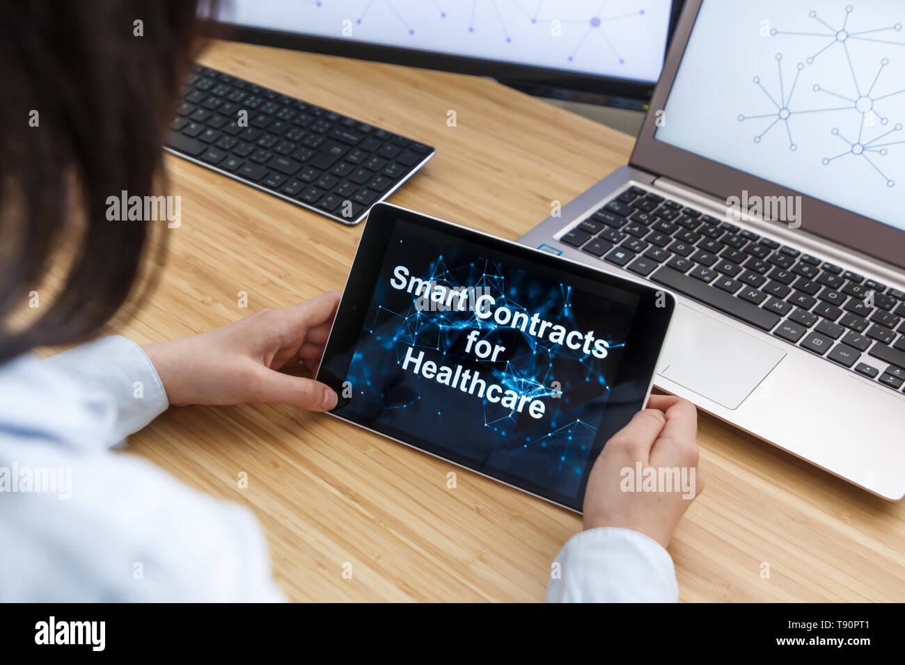 Business Weiblich mit Smart Verträge für das Gesundheitswesen. Abbildung des Astraleums Blockchain auf dem Bildschirm des Tablet-PC, PC und Laptop. Stockfoto