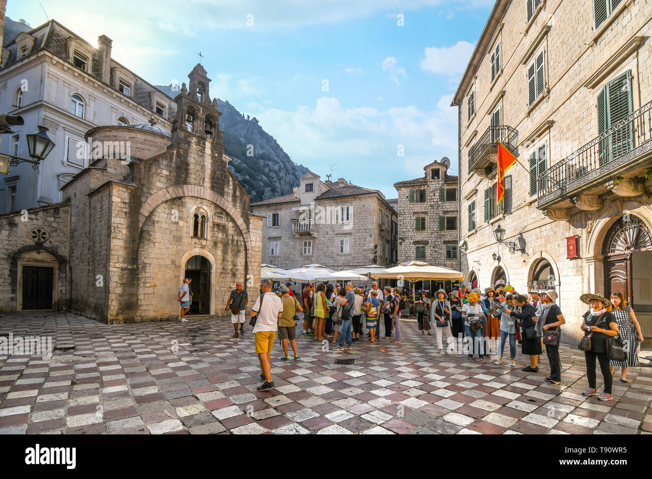Touristen versammeln sich auf St Luke's Platz vor der alten Kirche mit drei Glockentürme in Kotor, Montenegro. Stockfoto