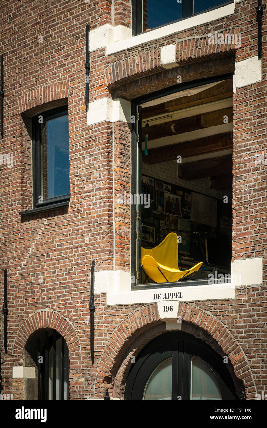 Gelbe Liegestuhl in der geöffneten Fenster im ersten Stock eines umgebauten Amsterdam Lager. Stockfoto