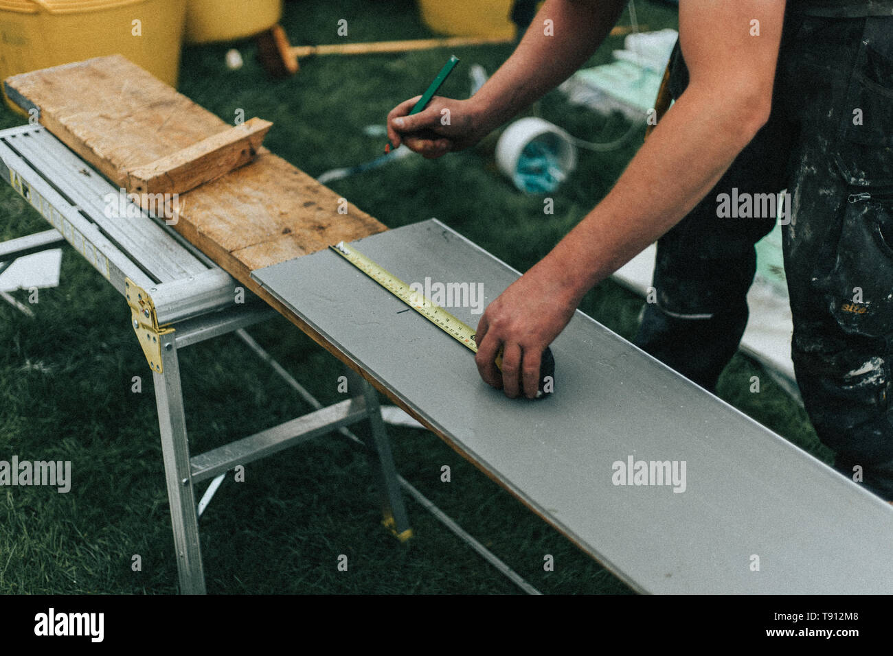 Builder arbeiten, Messen und Schneiden Boards für Renovierung und Unterhalt. Zeigt Werkzeuge und Ausrüstung mit Materialien im Hintergrund verwendet wird Stockfoto