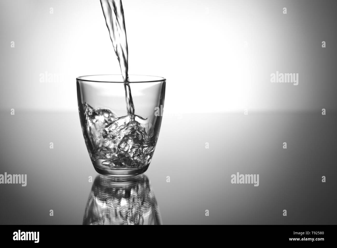 Das Gießen von Wasser im Glas auf dem Tisch Stockfoto