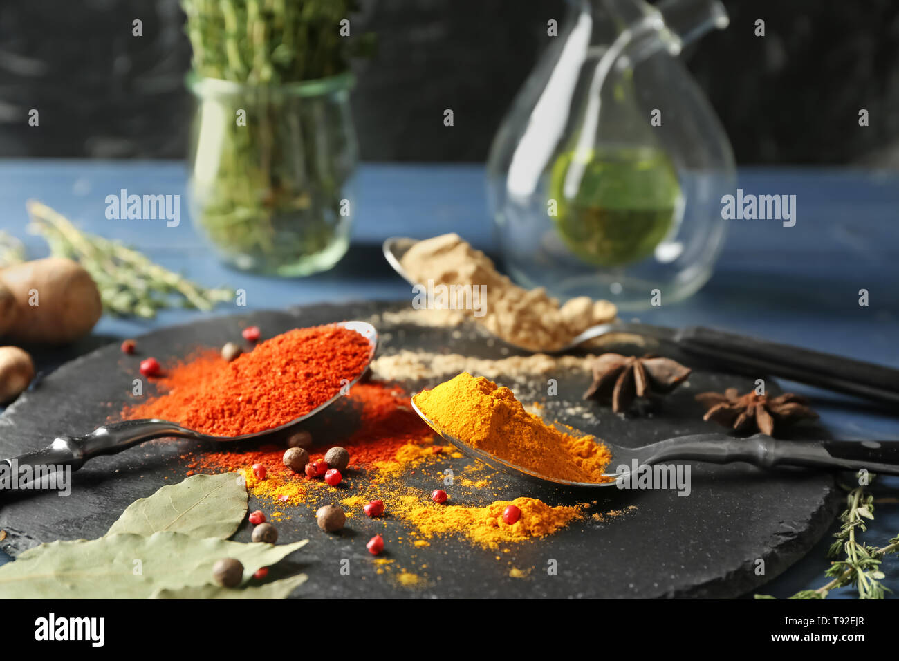 Löffel mit verschiedenen Gewürzen auf schiefer Platte Stockfoto