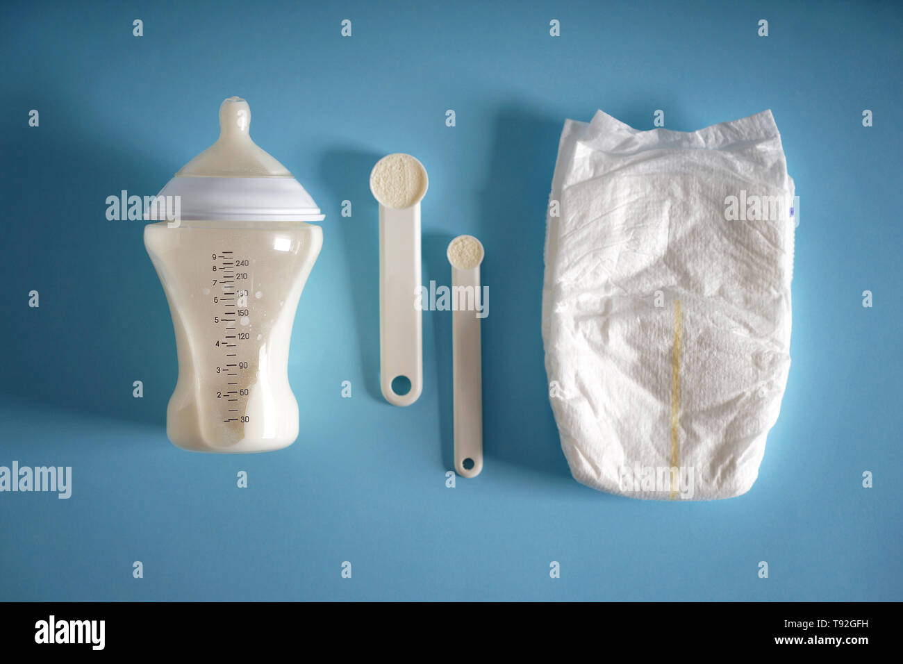 Die Flasche von Babynahrung mit Windel und Pulver auf farbigen Hintergrund Stockfoto