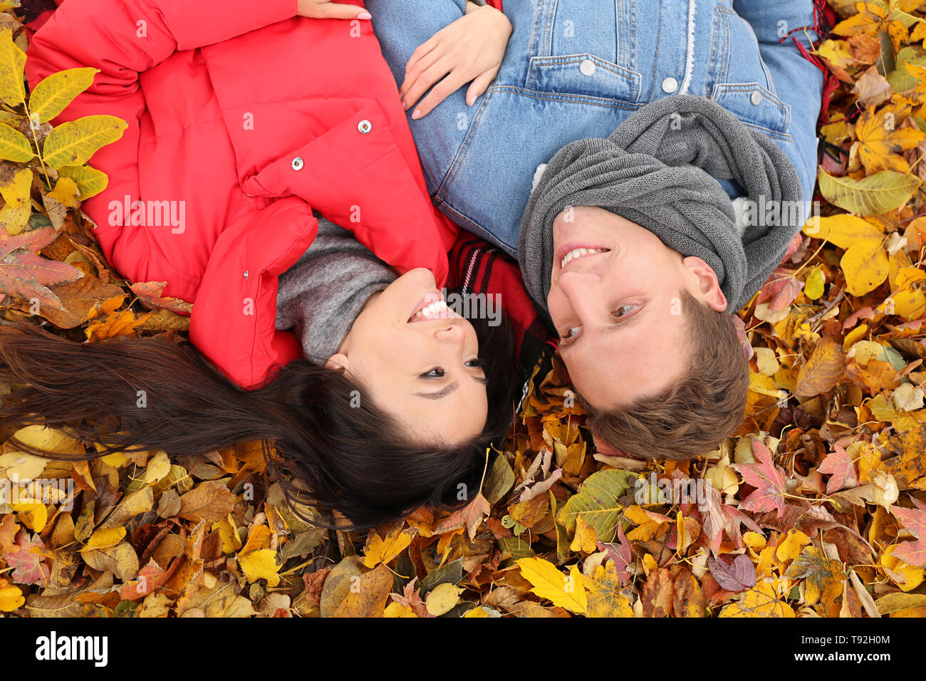 Liebevolle junge Paar liegt auf trockene Blätter im Herbst Park Stockfoto