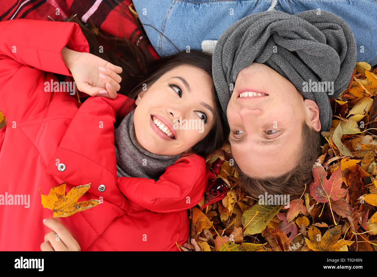 Liebevolle junge Paar liegt auf trockene Blätter im Herbst Park Stockfoto