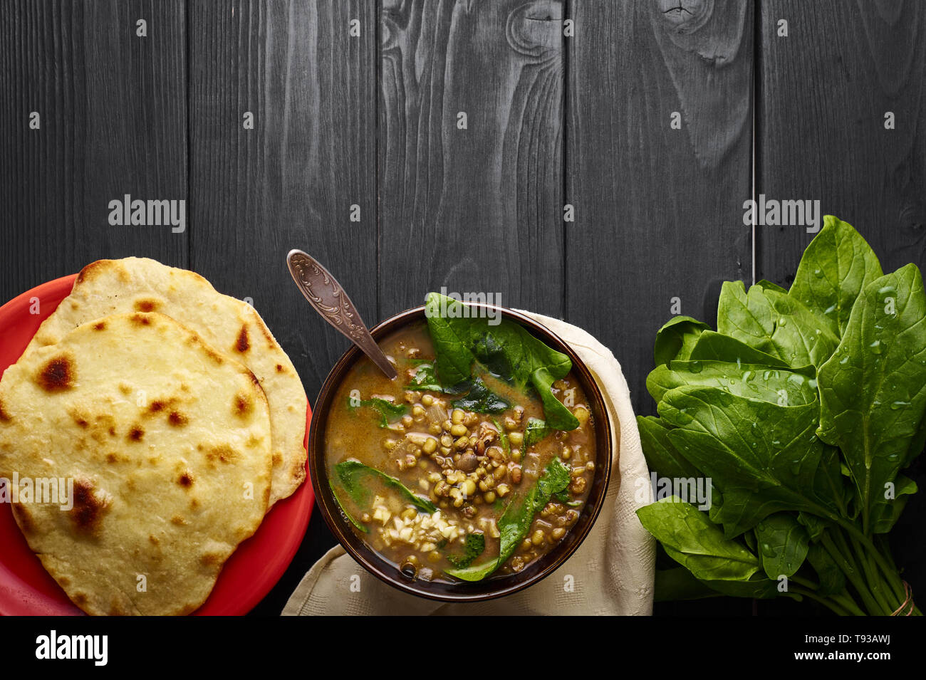 Mung dhal mit grünen Spinat und Chapati am schwarzen Holz der Tischplatte. Moong Dal - Indische Küche Curry. Vegetarische würzigen Gericht. Nach oben Ansichtskopie Raum Stockfoto