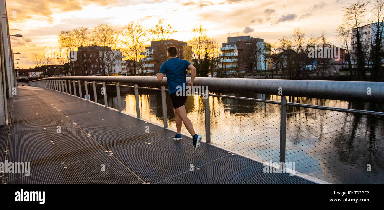 Jungen athletischen Mann Sport im Freien, schnell entlang der Brücke über den Sonnenuntergang Himmel Hintergrund. Überwinden von Hindernissen zu erobern und zu gewinnen. Er Stockfoto