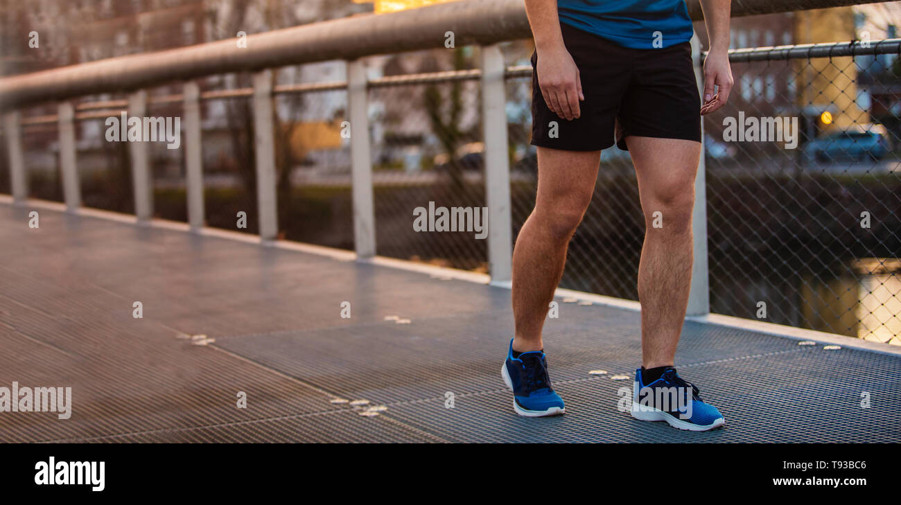 Der junge Mann sportliche Beine laufen im Freien entlang einer Brücke am Morgen. Überwinden von Hindernissen zu erobern und zu gewinnen. Gesunder Lebensstil Konzept Stockfoto