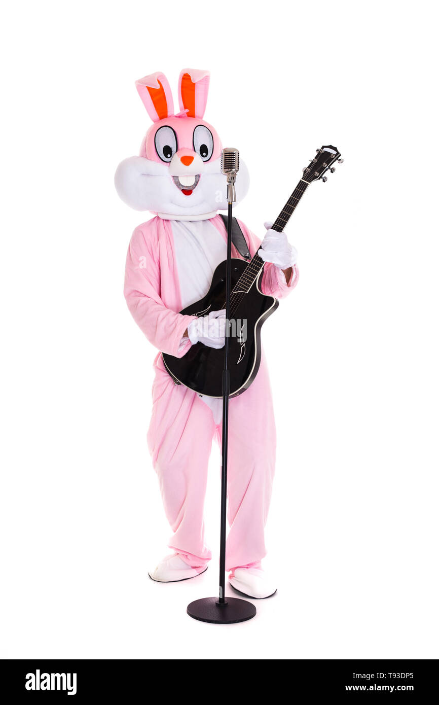Mann in einem Osterhase Kostüm spielt Musik auf Gitarre, singt mit retro Mikrofon, Spaß auf dem weißen Hintergrund haben. Lustige Hase oder Kaninchen Gitarrist Sänger Stockfoto