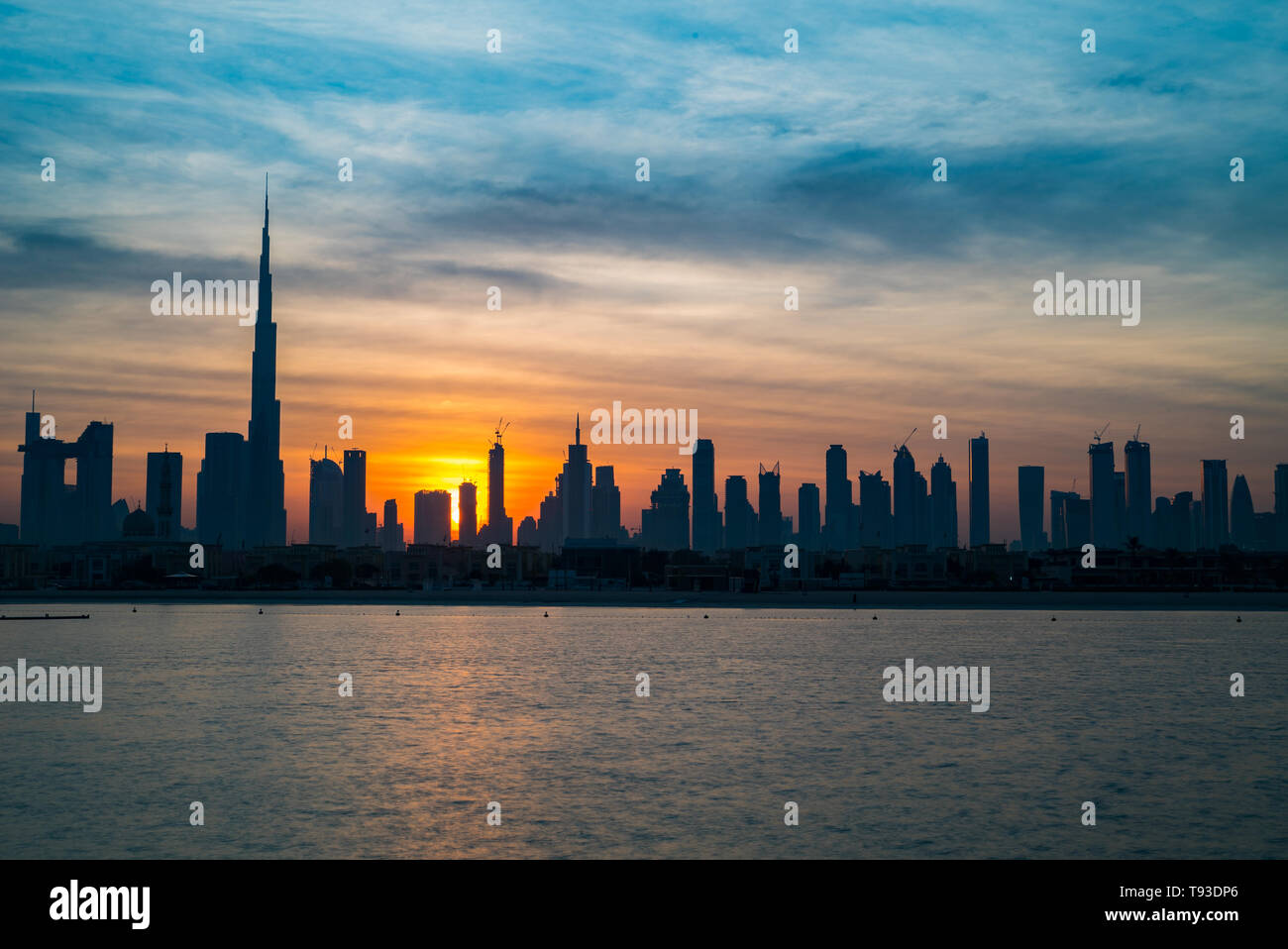 Sonnenaufgang in Dubai, Dämmerung über Wolkenkratzer in der großen Stadt. Morgen in Dubai, Sonne über Gebäude. Solar Pfad auf Meer oder Ozean. Der neue Tag mit Sun Stockfoto