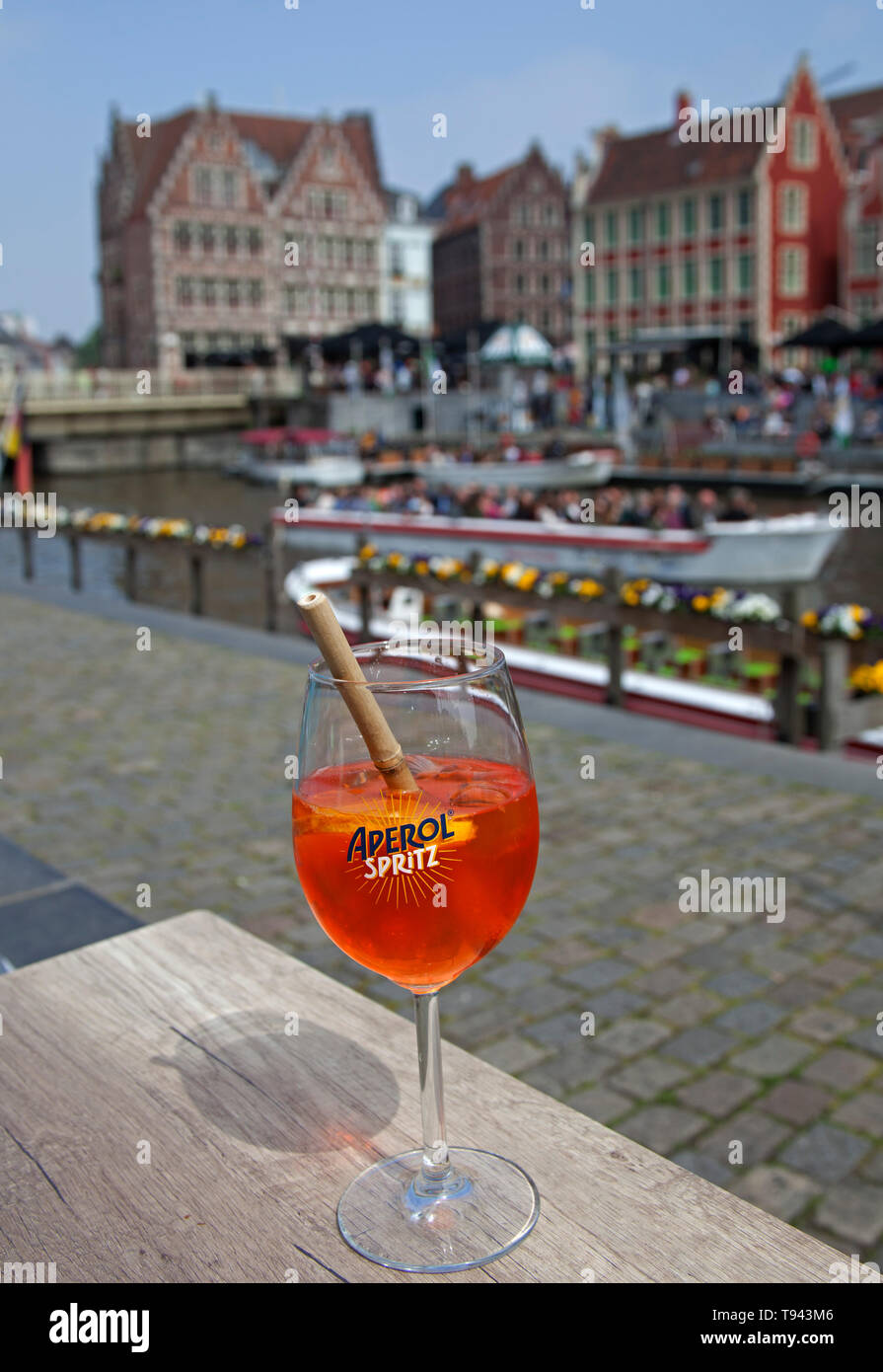 Aperol Spritz trinken auf cafe bar Tisch mit Flusses Leie Waterfront, und  touristische Boote auf dem Fluss im Hintergrund Stockfotografie - Alamy