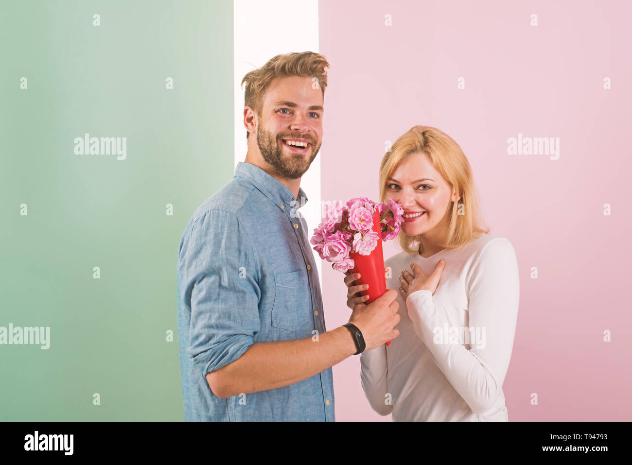 Mann gratuliert Frau Geburtstag Jubiläum Holiday, pastellfarbenen Hintergrund. Paar in der Liebe feiern Urlaub. Mann gibt Strauß Blumen zu Freundin. Geschenk Konzept. Paar Datum strauß blumen Geschenk. Stockfoto