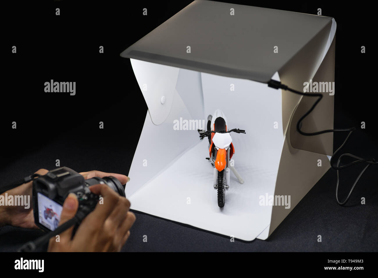 Amateur Fotograf auf spiegellosen Kamera zu schießen motrocycle Modell Mini lightbox arbeiten Stockfoto