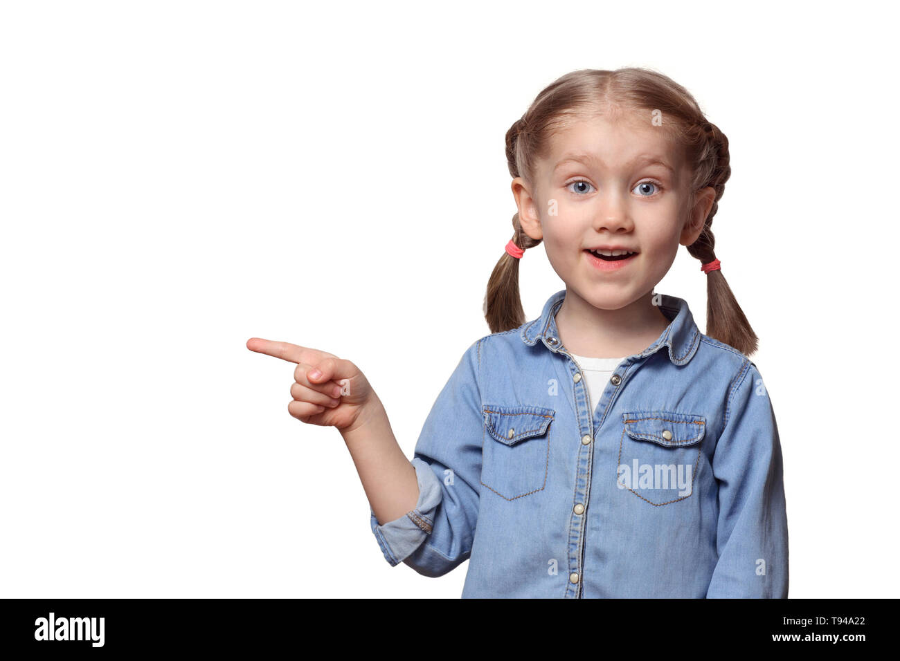 Das Kind zeigt auf etwas. Schöne Mädchen mit Zöpfen Punkten freudig mit einem Finger nach oben. Jugendlicher in einem Jeanshemd. Stockfoto