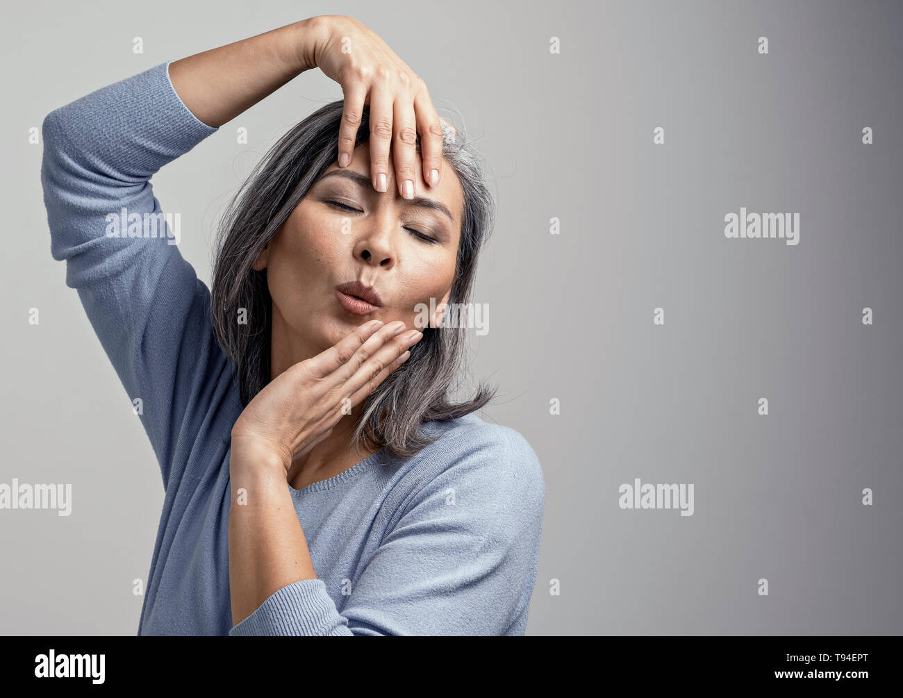 Attraktive Asiatin ist emotional posiert ihren Kopf mit den Händen berühren. Stockfoto