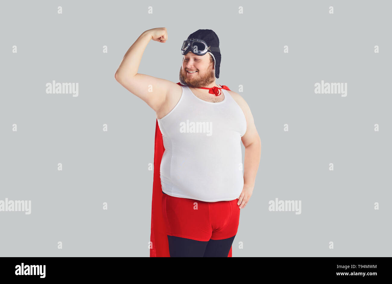 Funny fat man in einen Superhelden Kostüm hob die Hand. Stockfoto