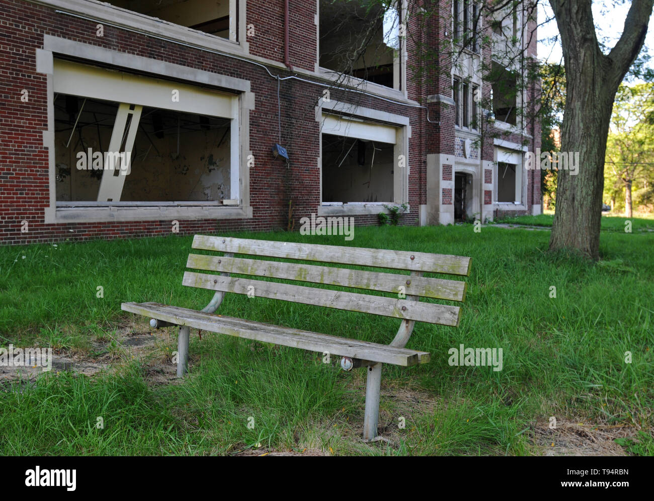 Eine Holzbank sitzt vor einem verlassenen öffentliche Schule in Detroit, Michigan. Alle Gebäude, Fenster und Türen wurden gebrochen oder entfernt. Stockfoto
