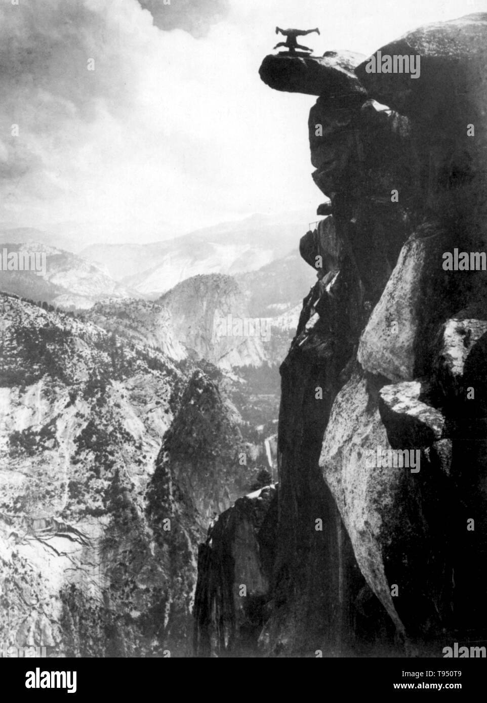 Junger Mann auf dem Kopf auf dem Glacier Point ausgeglichen. Glacier Point ist ein Aussichtspunkt über Yosemite Valley in Kalifornien, USA. Es ist an der Südwand von Yosemite Tal auf einer Höhe von 7,214 Metern. Der Punkt bietet einen herrlichen Blick auf, die verschiedenen der Yosemite National Park bekannten Sehenswürdigkeiten, wie Yosemite Valley, Yosemite Falls, Half Dome, Vernal Fall, Nevada Fall, und Wolken. 1890s Stockfoto