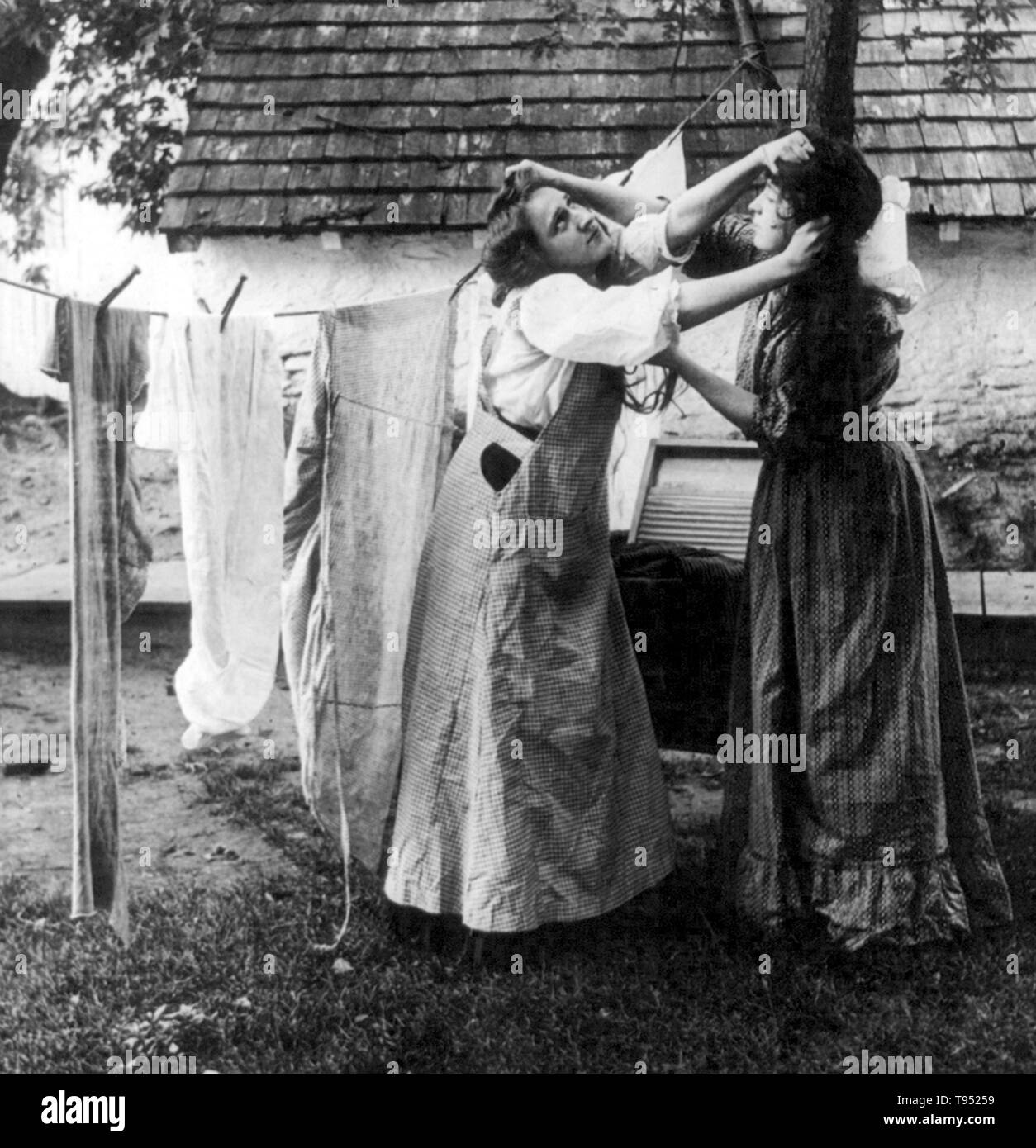 Mit dem Titel: "Mühe auf der Linie' zeigt zwei Frauen ziehen sich gegenseitig die Haare vor der Wäscheleine. 7/8 stereograph fotografiert von E.W. Kelley, 1906. Stockfoto