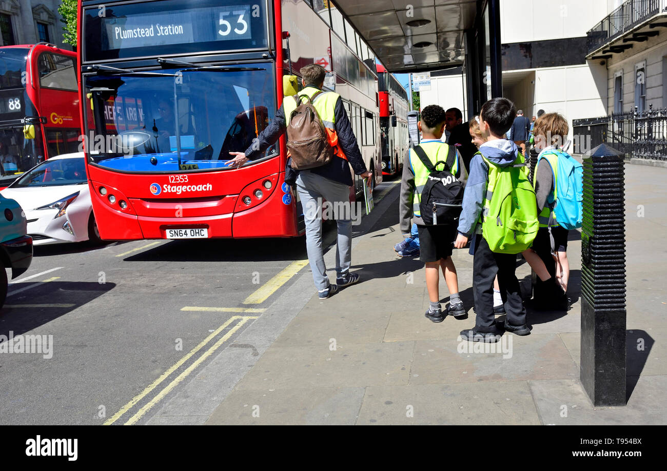 London, England, UK. Gruppe junger Schüler warten auf einen Bus zu erhalten Stockfoto