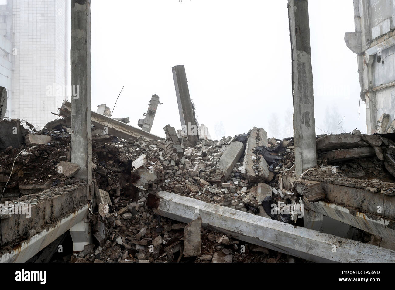 Die zerstörte große Gebäude aus Beton in einer nebligen Dunst. Die Überreste der Rahmen des grauen Betonpfeilern und Ablagerungen von der Gebäudestruktur. Hintergrund. Stockfoto
