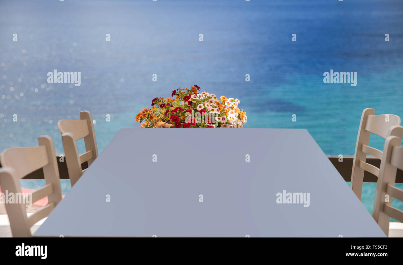 Tisch mit Stühlen mit Blick auf das Mittelmeer. Blumen im Hintergrund. Stock Bild. Stockfoto