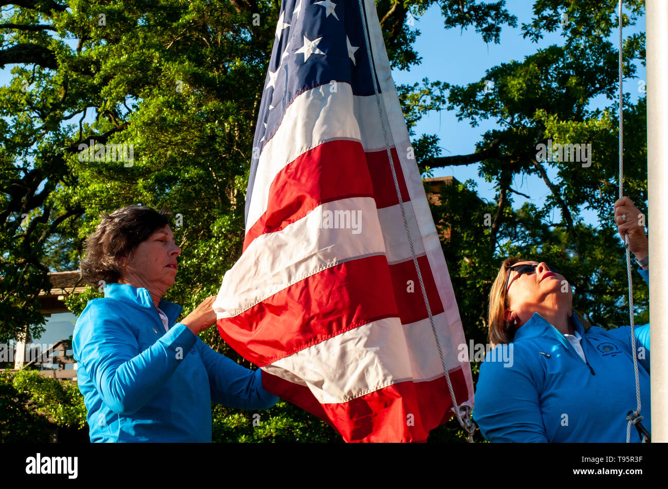 Southern Pines, North Carolina, USA. 16. Mai, 2019. Mai 16, 2019 - Southern Pines, North Carolina, USA - BONNIE McGOWAN, Links, und ihre Schwester, Peggy, Miller, sowohl der südlichen Kiefern und Töchter der späten Peggy Kirk Bell, heben Sie die amerikanische Flagge bei der Eröffnungsfeier in der ersten Runde die USGA 2 U.S. Senior Frauen Offene Meisterschaft im Pine Needles Lodge and Golf Club, 16. Mai 2019 in Southern Pines, North Carolina. Peggy Kirk Bell, merkte Golf der Frauen befürworten, Lehrer, ehemalige LPGA Tour player, und World Golf Hall of Fame Mitglied, im Besitz von Tannennadeln vor ihrem Tod im Jahr 2016. Pi Stockfoto