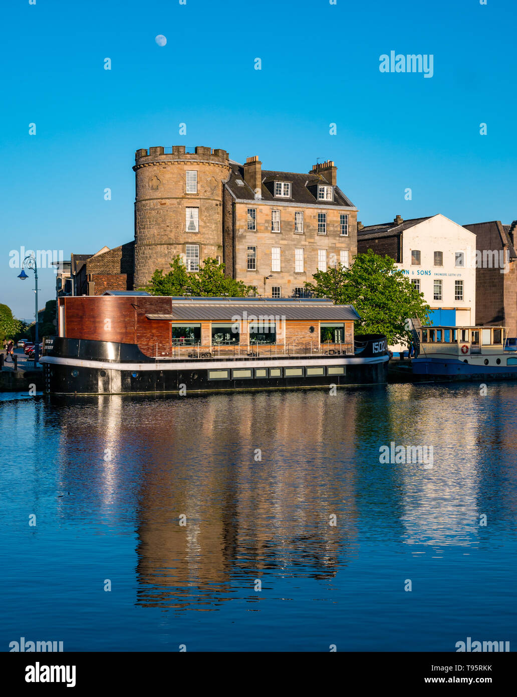 Leith Docks, Edinburgh, Schottland, Großbritannien, 16. Mai 2019. UK Wetter: ein sonniger Tag geht zu Ende über den Hafen in Leith mit Gebäuden und Lastkähne auf dem Ufer von den letzten Strahlen der Sonne spiegelt sich im Wasser des Leith Fluss lit Stockfoto