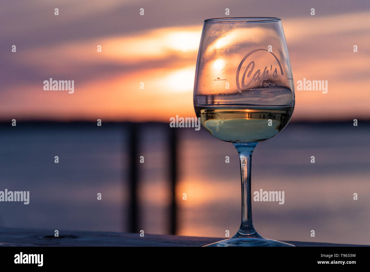 Farbenfroher Sonnenuntergang mit Glas Wein am Wasser Dock an Caps auf dem Wasser, ein lokales Seafood Restaurant in St. Augustine, Florida. (USA) Stockfoto