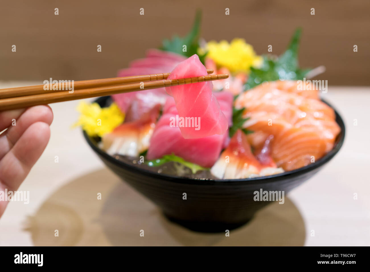 Stäbchen mit Thunfisch-sashimi mit gemischten geschnittenen Fisch sashimi auf Eis im schwarzen Schüssel. Sashimi Lachs Thunfisch Hamachi Garnelen und Surf Ruhig, roher Fisch, Japan Stockfoto