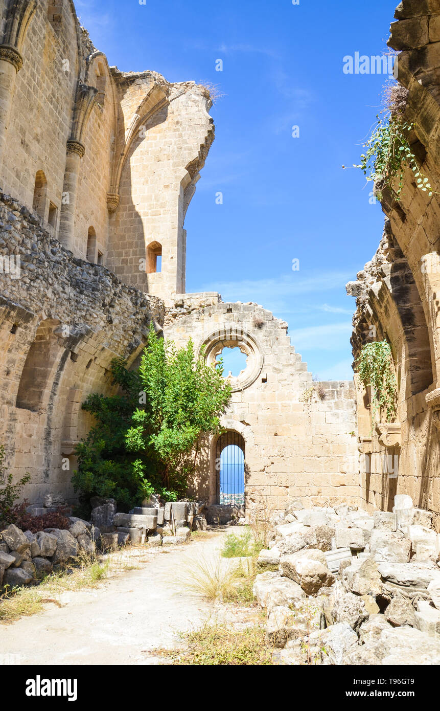 Ruinen von den Wänden der schönen Bellapais Abbey in Bellapais, Nordzypern. Das historische Kloster in den türkischen Teil der Insel mit blauem Himmel auf einer vertikalen Bild aufgenommen. Beliebte Attraktion. Stockfoto