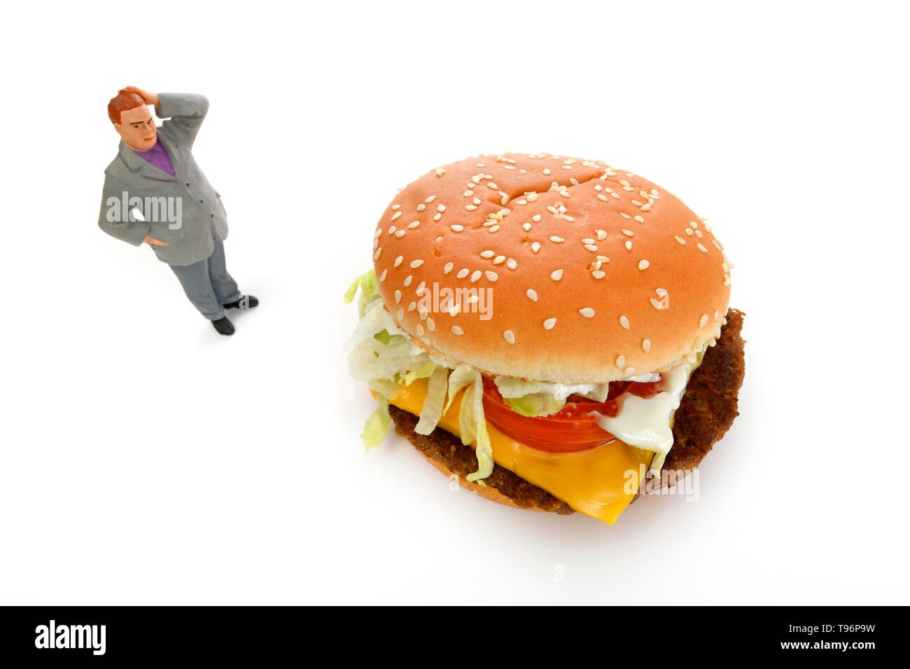 Symbol Bild Übergewicht, ungesunde Ernährung, nachdenkliche Figur vor der Cheeseburger, Deutschland Stockfoto